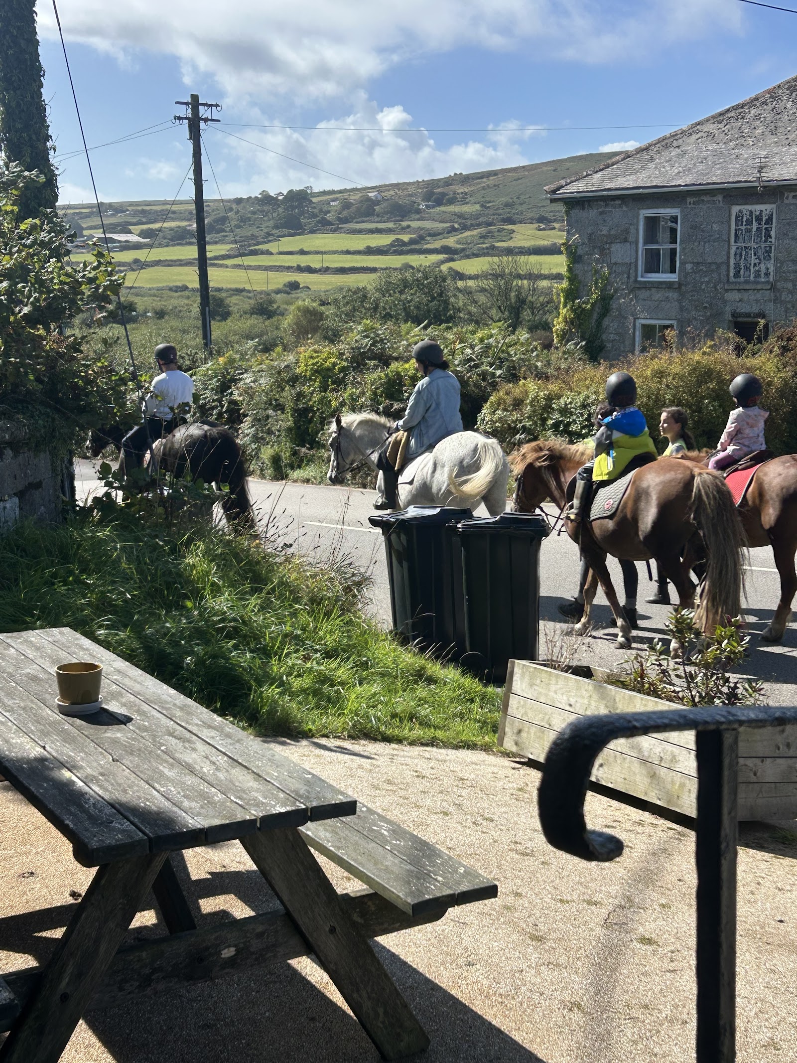 Riders on horseback passing the inn, with the moor rising behind