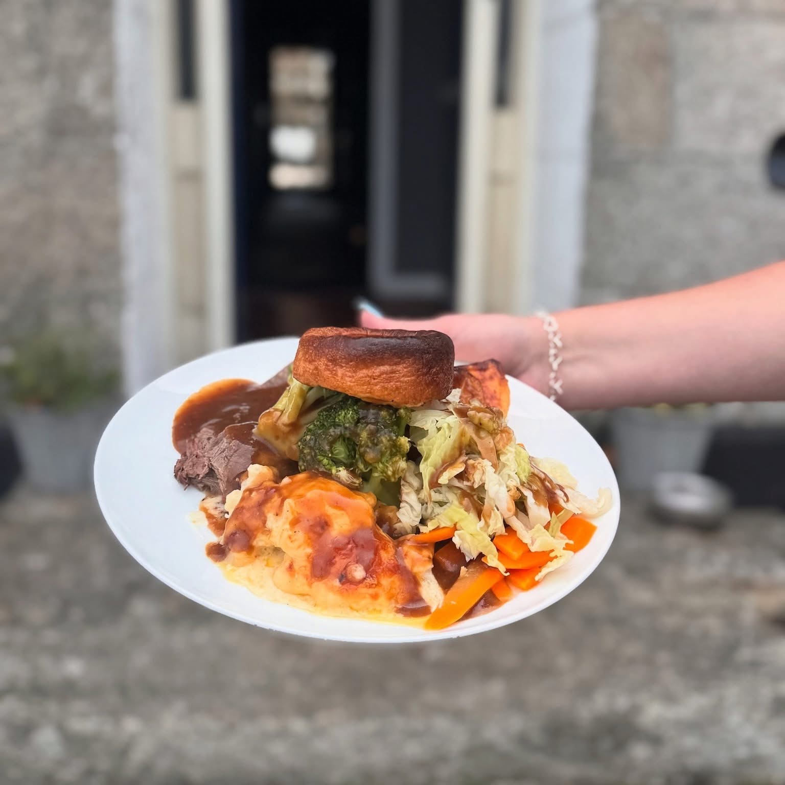 A Sunday roast with Yorkshire pudding, held up before the inn's granite doorway