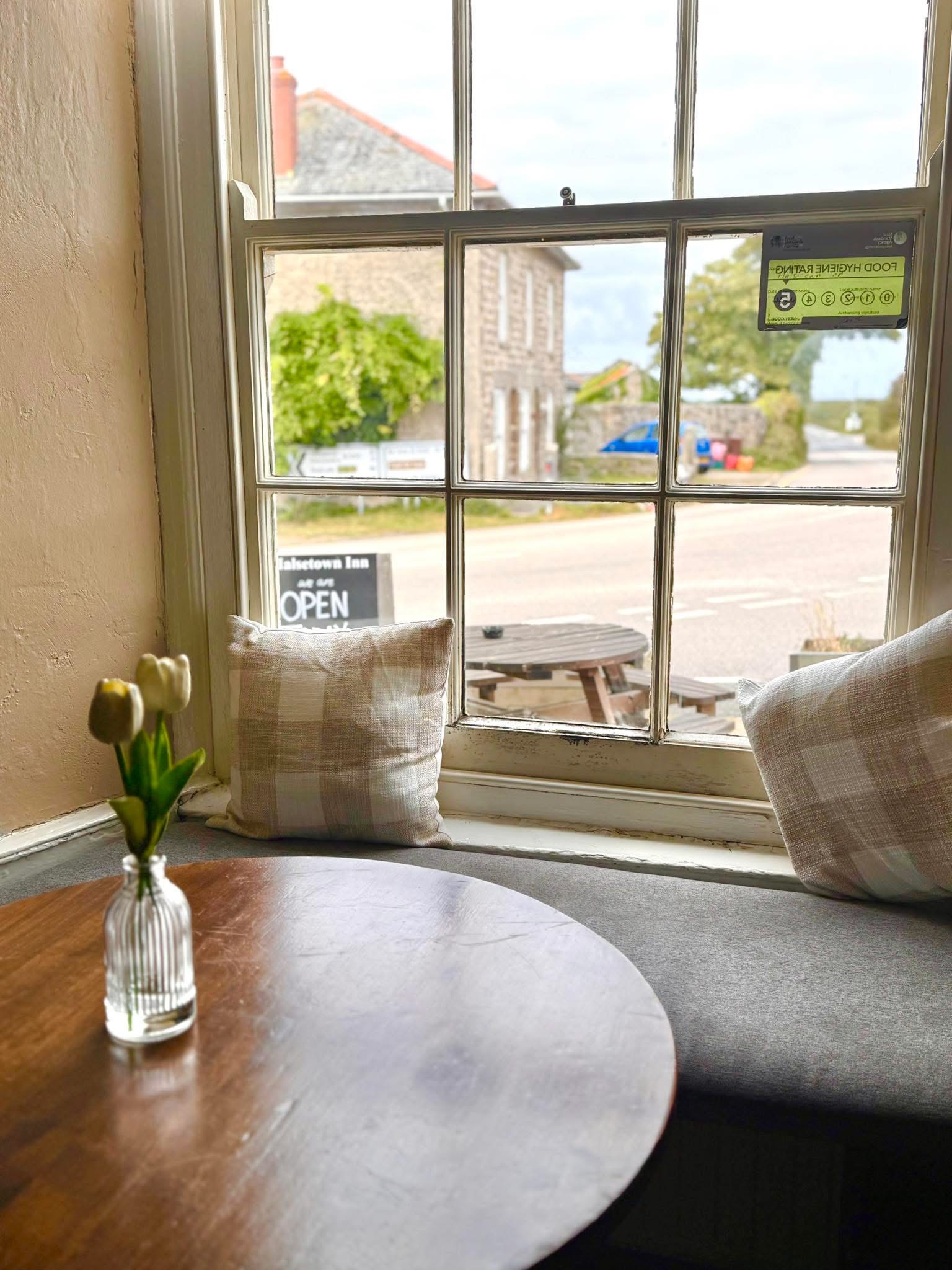 A window seat inside the inn — tulips on the table, the village lane beyond the sash window